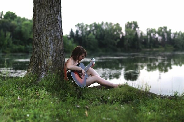 A girl with a guitar on the lake shore