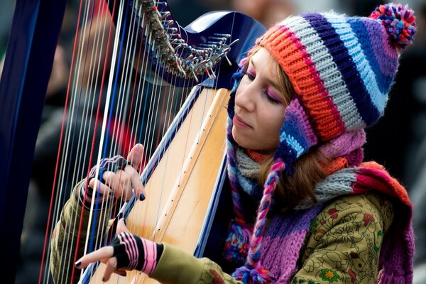 Chica tocando el arpa de un sombrero de colores