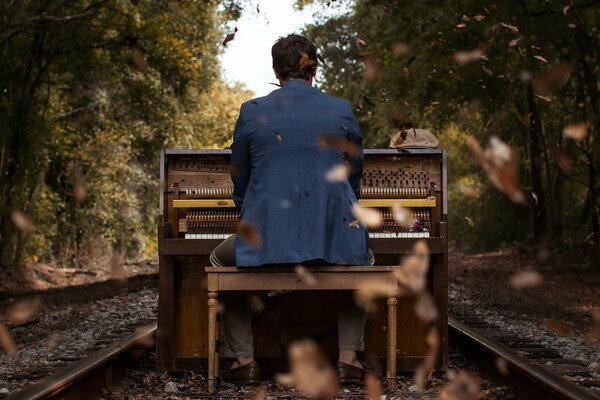 Against the background of an autumn landscape, a guy plays the piano