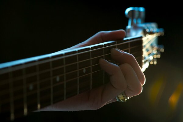 La mano stringe le corde della chitarra