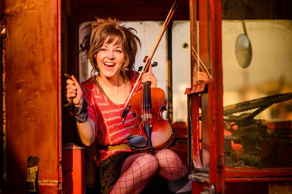 Lindsay Stirling with a violin on a red bus