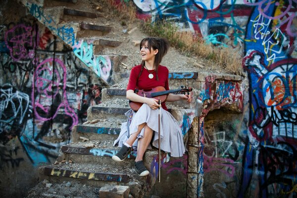 A cheerful violinist on the background of an abandoned building