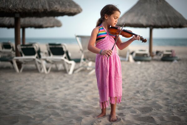 A little girl in a pink dress plays the violin