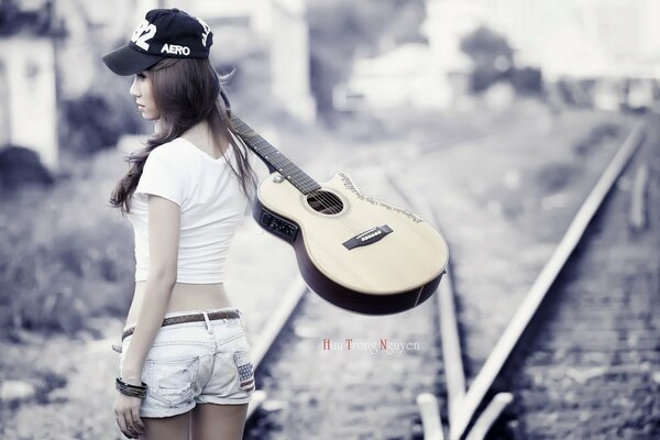 Fille avec une guitare sur les rails du train