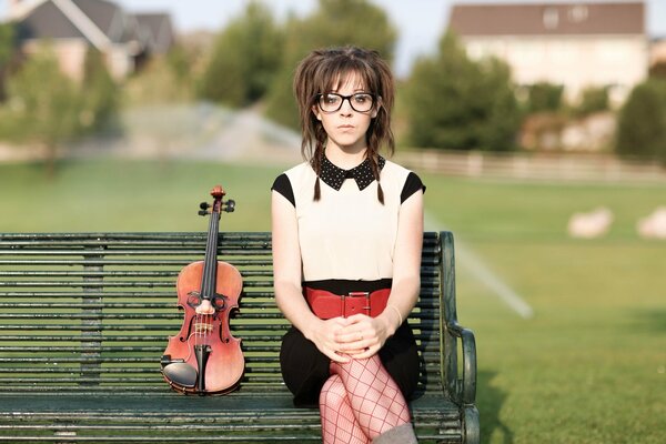 The girl is not on the bench and next to the violin