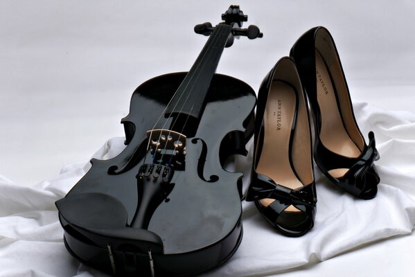 Black violin and black shoes on white fabric