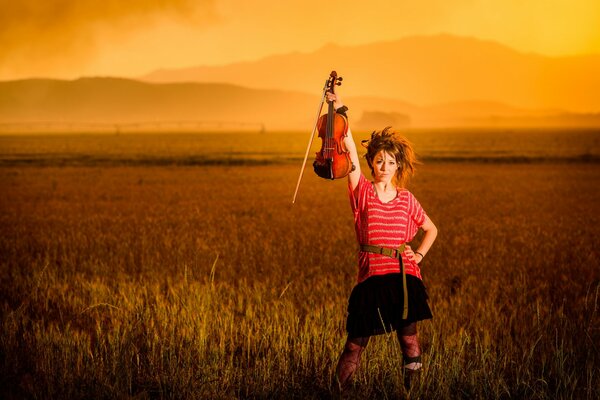 Chica violinista al atardecer en el campo