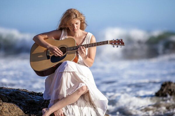 CHICA TOCANDO N GUITARRA JUNTO AL MAR