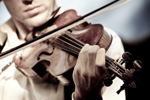 A man plays the violin on a dark background