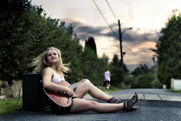 Una chica al atardecer con una guitarra en la mano