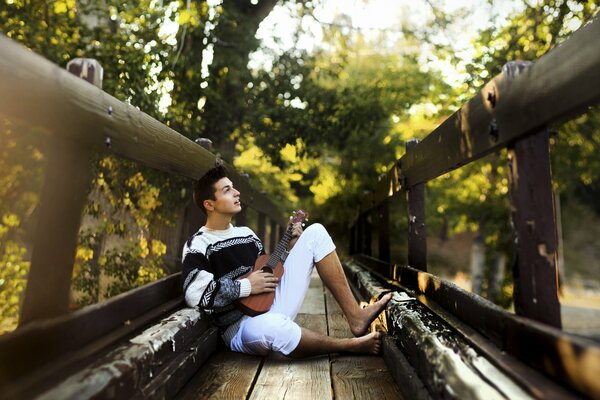 A young guy with a guitar on the bridge