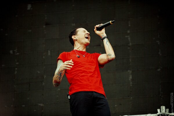 Un homme en t-shirt rouge chante au micro