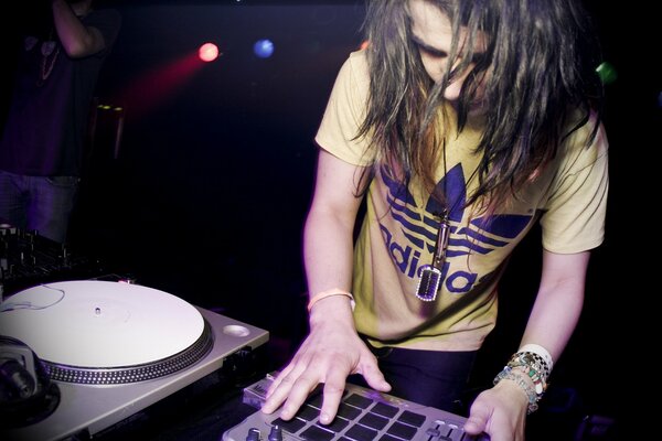 DJ at work in a stylish T-shirt playing dubstep music