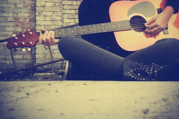 Chica se sienta y toca la guitarra