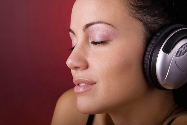 A girl listens to music with headphones with her eyes closed