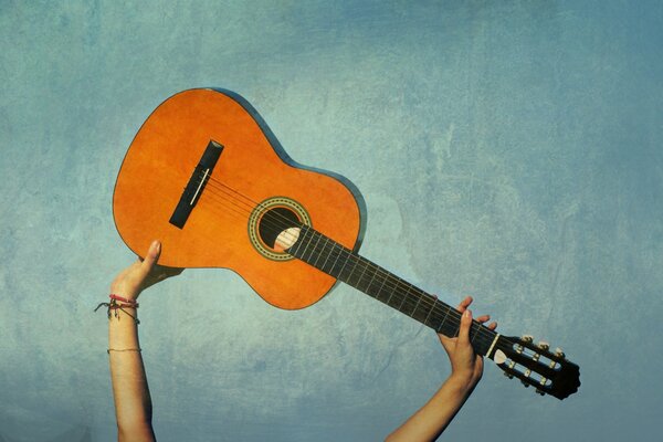 La guitarra se sostiene sobre un fondo azul