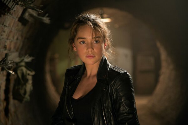 Ein Rahmen aus dem Film Terminator: Genesis, in dem die Heldin Emilia Clarke in einer Lederjacke vor einem Hintergrund eines Steingewölbes steht