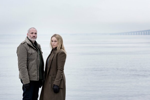 A man and a woman warmly dressed are standing in the sea