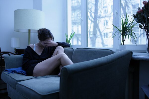 Mädchen sitzt mit geschlossenem Gesicht auf der Couch