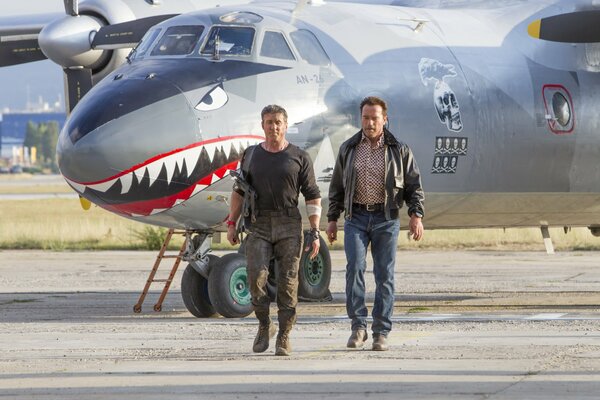 Sylvester stallone und arnold Schwarzenegger im Hintergrund eines Flugzeugs