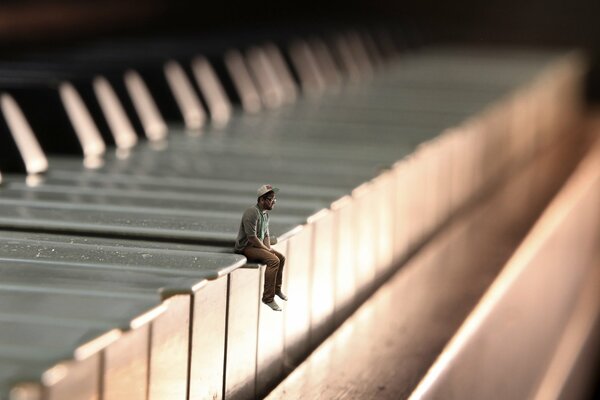 Pequeño hombre sentado en el piano