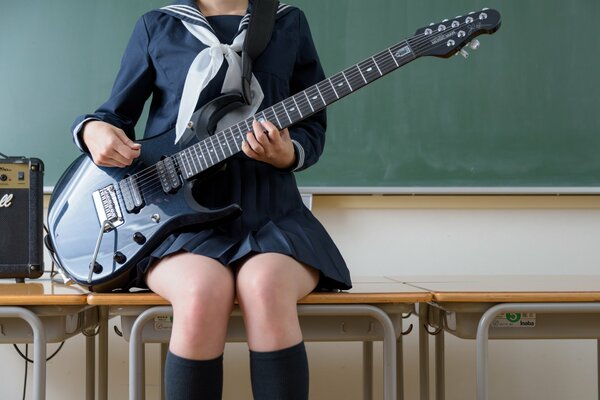 Legs of a girl sitting on a table with a guitar in her hands