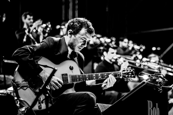 Photo of an orchestra with a guitarist in the foreground