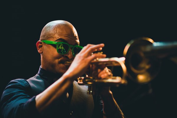 Musiker mit grüner Brille spielt Trompete bei Nachtlicht