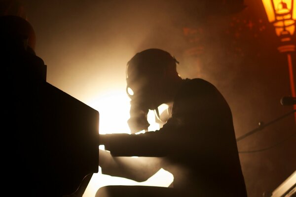 A picture from below of a pianist in a gas mask