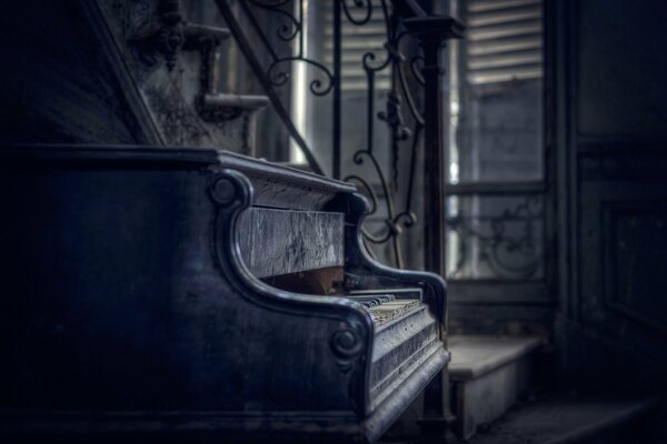 Antique piano with open keys in the dust