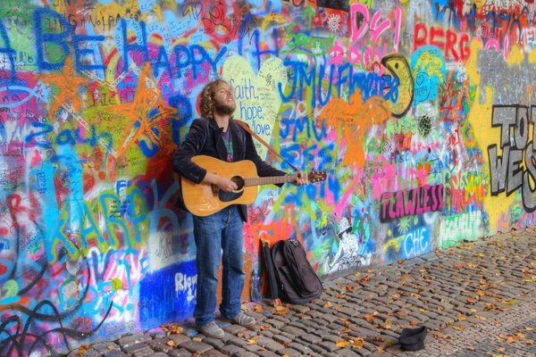 Músico toca la guitarra mientras está de pie contra la pared