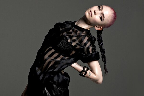 Canadian singer Grimes in a transparent blouse and with a braid