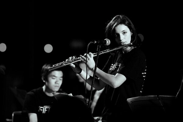 La ragazza suona il flauto. Musicista in sottofondo