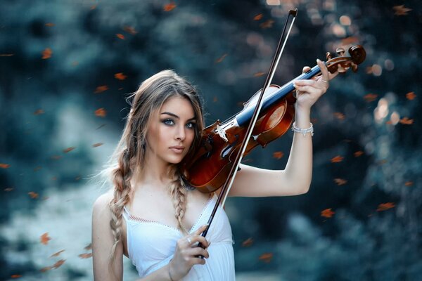 A girl with a violin is playing in the forest