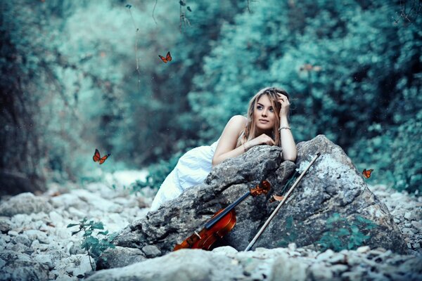 Hermosa chica en una piedra con un violín