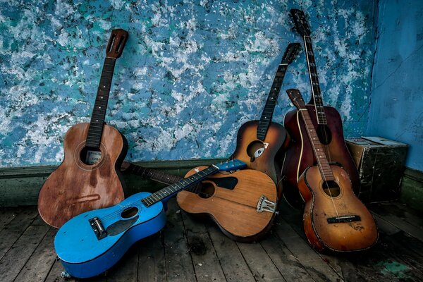 Seis viejas guitarras apiladas en una esquina