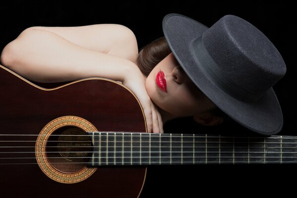 Chica con sombrero con lápiz labial rojo y guitarra