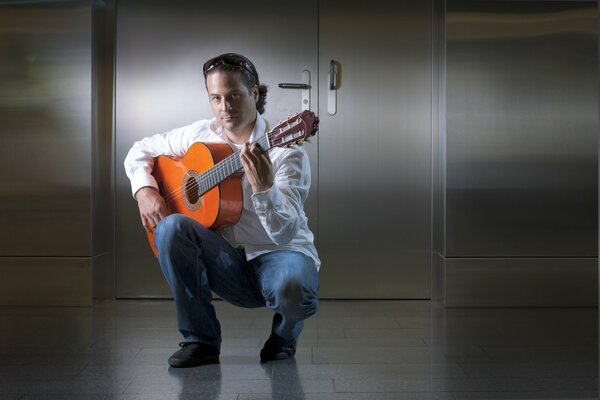 Guitarist David in a white shirt and blue pants holds a guitar