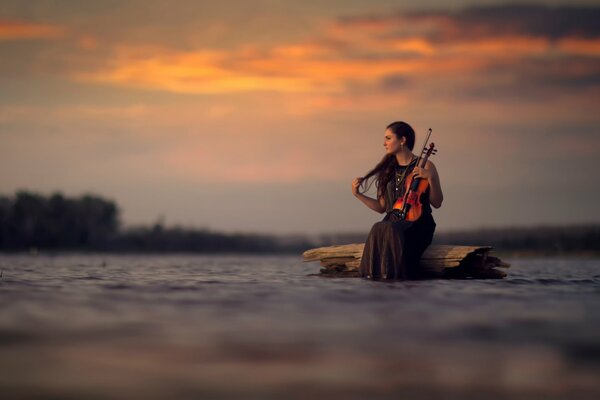 Chica con violín en medio del agua