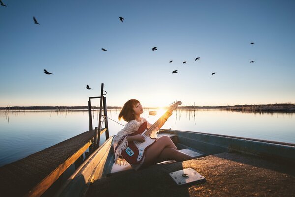 Una chica con una guitarra sentada en un lago