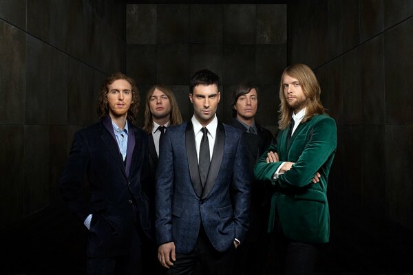 Groupe maroon 5 en costumes debout sur fond sombre