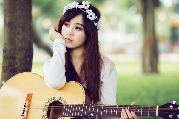 A girl in a wreath with a guitar in a white dress