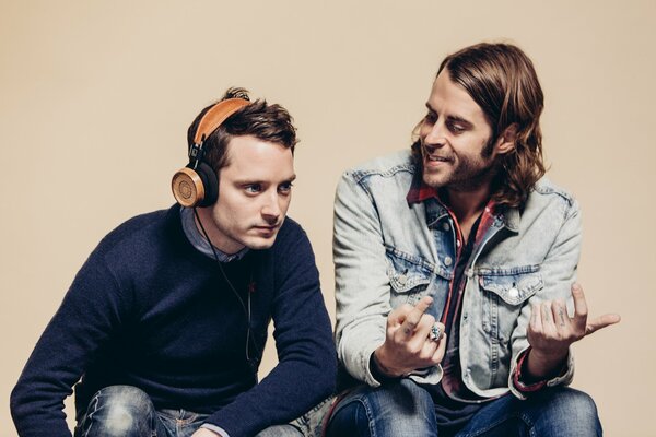 Elijah Wood y Zach Cowie están hablando. Hombre en auriculares