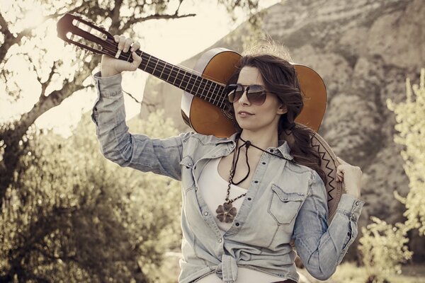 Fille avec une guitare à la main dans la forêt