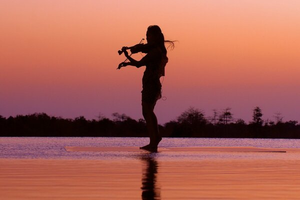 A girl plays the violin at night