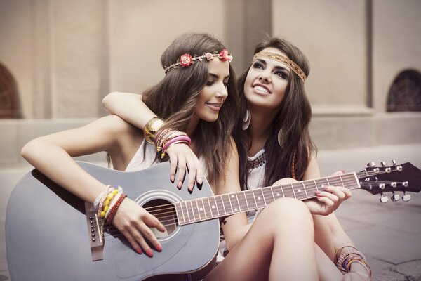 Due ragazze hippie che suonano la chitarra