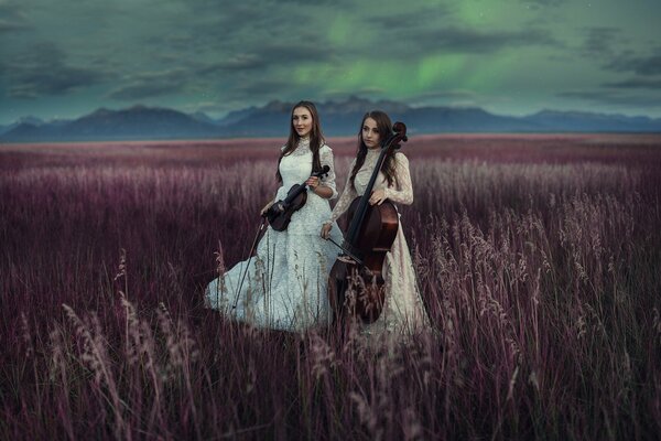 Two girls in a field playing the violin