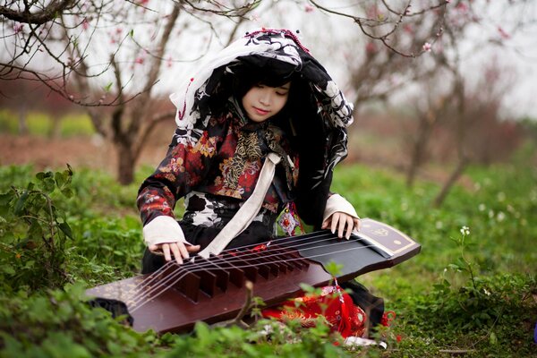 A girl with a musical instrument in the garden