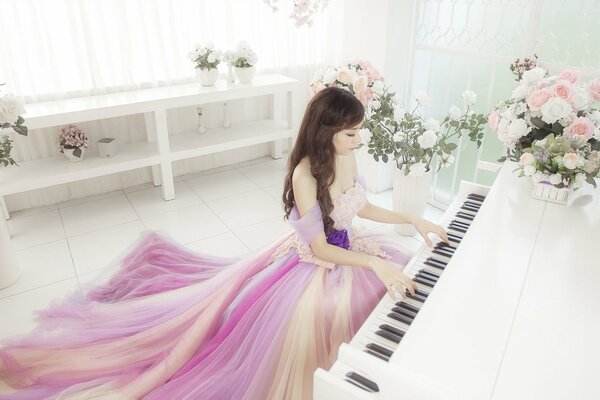 A girl in a dress plays the piano