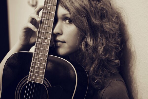 Bella ragazza con una chitarra nera asiatica